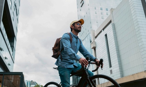 A man with a backpack riding a bicycle in the city